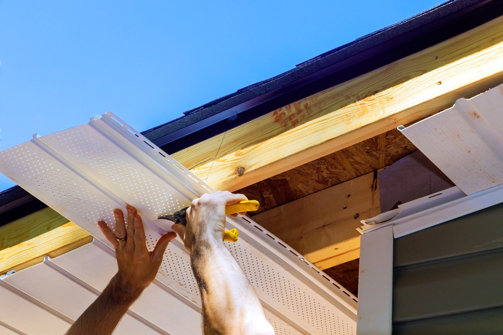 Vinyl soffit plastic panels into facade ceiling of a new house by an employee